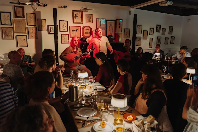 Two men singing and performing during a fado show in Lisbon as the crowd looks on.