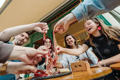 Guests eating ham in Lisbon during a food tour, laughing and smiling.